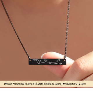 A close-up of a hand holding a black bar necklace with a white engraved design, against a warm brown background. A beige banner at the bottom reads: 'Proudly Handmade in the USA | Ships Within 24 Hours | Delivered in 2-4 Days'.