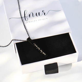 A silver-toned bar necklace with the handwritten inscription 'I love you my son.' displayed on a black velvet jewelry box inside a white presentation box branded 'fnur JEWELRY DESIGN'.