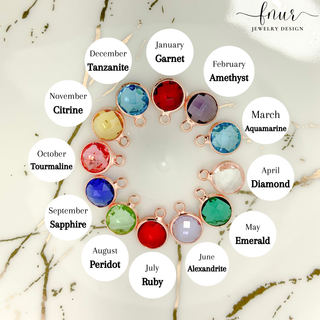 A circular jewelry display featuring twelve rose gold bezel settings with faceted gemstones, each labeled with its corresponding month and gemstone name on white circular callouts over a light marble background. The brand name 'fnur JEWELRY DESIGN' appears in the top right corner.