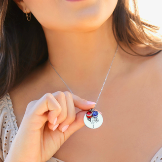 Necklace with a round pendant featuring colorful stones held by a person.