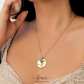 A close-up lifestyle shot of a model wearing a gold chain necklace with a round gold pendant. The pendant features a small turquoise blue stone and the engraved words 'Cruel World' with a small floral design.