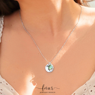 A close-up of a model's neck and chest wearing a delicate silver chain necklace with a round silver pendant featuring a green stone and small floral details. The brand name 'fnur jewelry design' is visible as a watermark at the bottom.